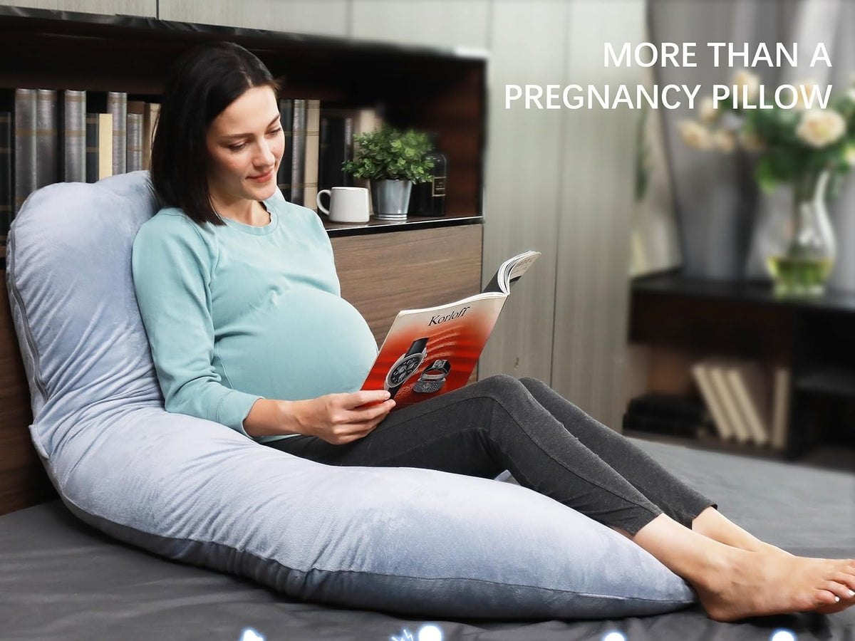Pregnant woman sitting up in bed reading with the pregnancy pillow supporting her whole back