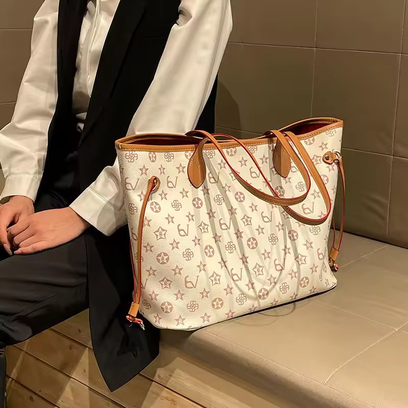 Cream patterned tote with tan handles beside a seated woman